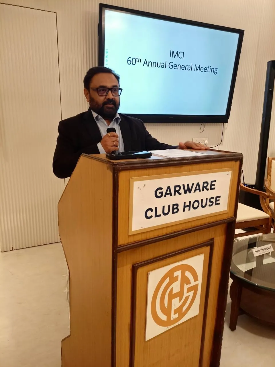 Kirtiraj Gohil speaking at a lectern marked Garware Club House; the screen behind him reads “IMCI 60th Annual General Meeting”